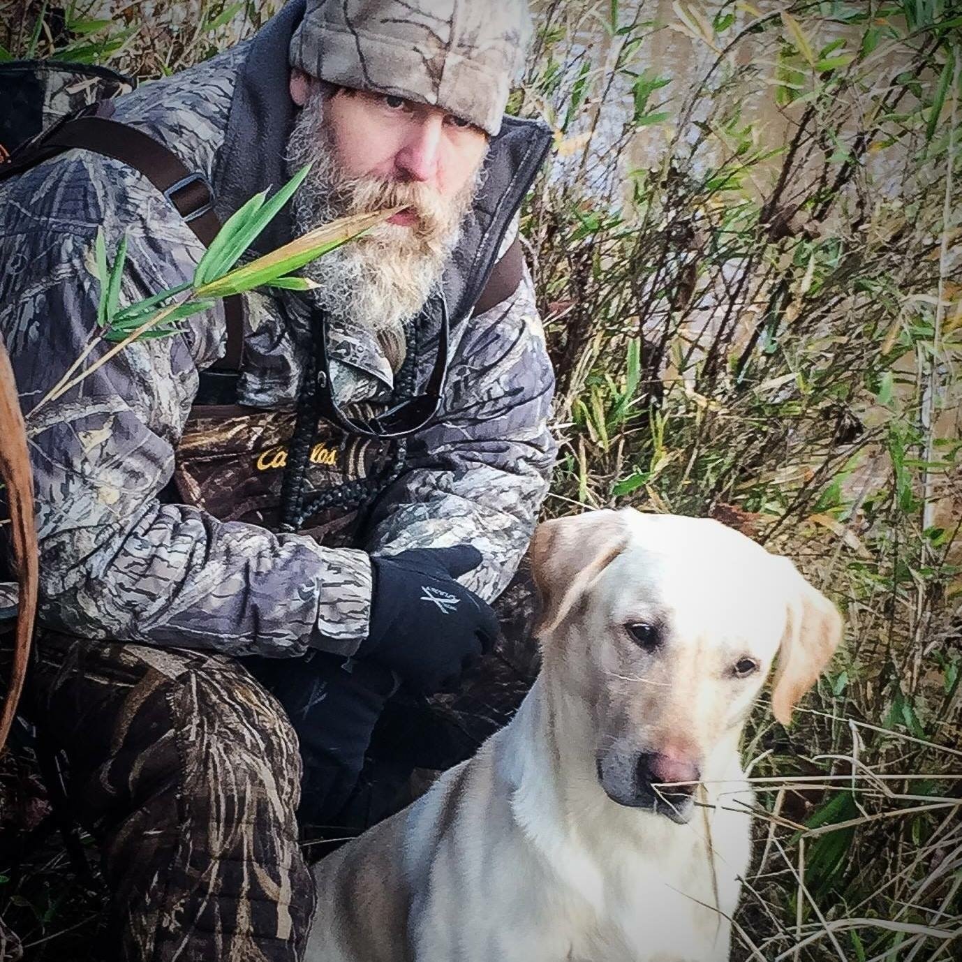 Charles Watson kneeling in the cover with his yellow lab